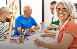 Mujer mayor en una clase de pintura y sonriendo