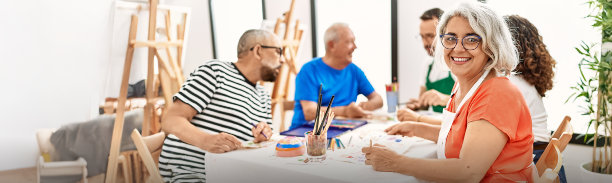 Mujer mayor en una clase de pintura y sonriendo