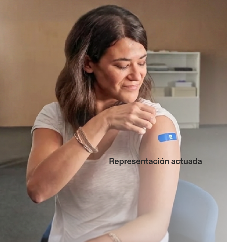 Representación actuada de un médico adulto observando a una mujer con la manga arremangada y una curita de Pfizer en el brazo