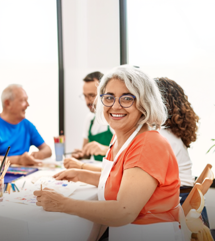 Mujer mayor en una clase de pintura y sonriendo