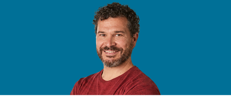 Hombre adulto sonriendo sobre un fondo azul